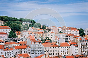 A large orange building with a mountain in the background. View of the rooftops of Lisbon. Portugal