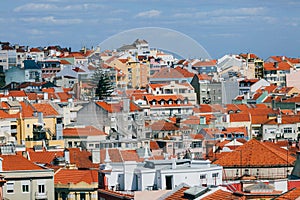 A large orange building with a mountain in the background. View of the rooftops of Lisbon. Portugal