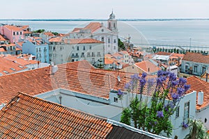 A large orange building with a mountain in the background. View of the rooftops of Lisbon. Portugal