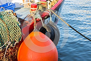 Large orange buoy on red fishing boat.