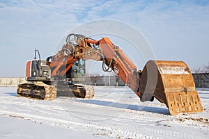 Large orange powerful crawler excavator pulling the boom with a bucket forward at a construction site