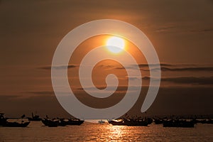 Large Sun Disk over Ocean with Boat Silhouettes at Sunset