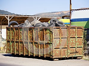 Large overflowing garbage container filled with worn-out tires