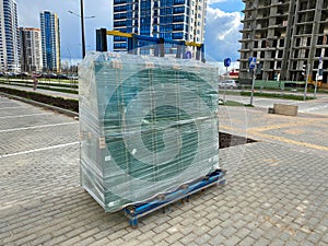 A large package of glass for windows of double-glazed windows wrapped with stretch film on the working site during the