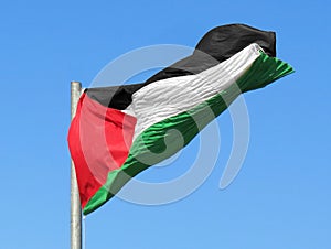 large Palestinian flag waving in the blue sky