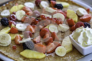 Large pancake with fresh summer fruit and whipped cream. Close-up