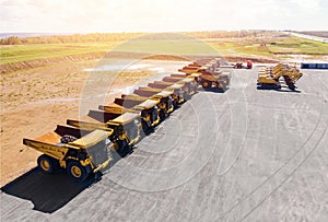 Large parking lot with big yellow mining truck, bulldozers for coal industry, ore and gold. Concept sale of industrial