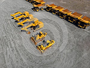 Large parking lot with big yellow mining truck, bulldozers for coal industry, ore and gold. Concept sale of industrial