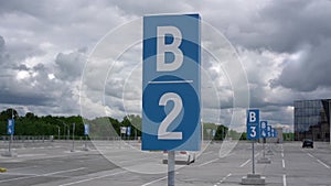 Large parking lot with grey asphalt and blue road signs