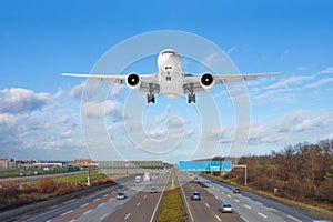 Large passenger aircraft landing over high speed highway