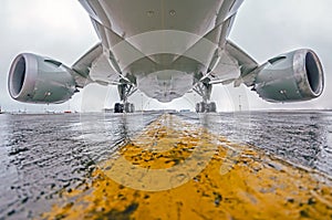 Large passenger aircraft parked at the airport, bottom view, chassis and engines.