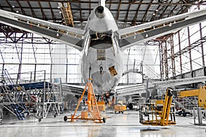 Large passenger aircraft on service in an aviation hangar rear view of the tail, on the auxiliary power unit.