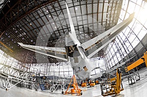 Large passenger aircraft on service in an aviation hangar rear view of the tail, on the auxiliary power unitand tail altitude cont photo