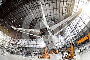 Large passenger aircraft on service in an aviation hangar rear view of the tail, on the auxiliary power unitand tail altitude cont