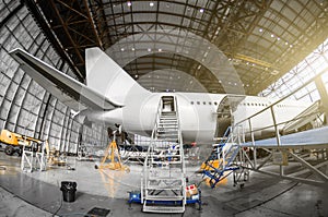 Large passenger aircraft on service in an aviation hangar rear view of the tail, gangway ladder entrance.