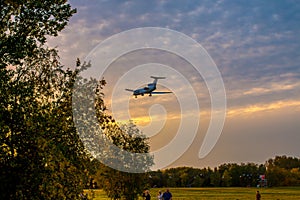 A large passenger plane goes on landing at sunset. shooting in the park against the background of autumn trees