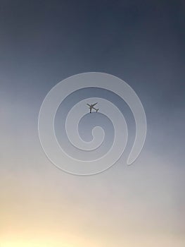 A large passenger plane with wings flies, soars high in the blue sky at sunset