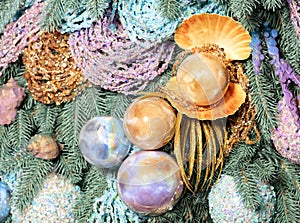 Large pearl balls with gold, pink and blue tint hang on the decorative branches of the Christmas tree. New Year decorations of sea