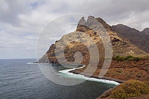 large pebble mountain by the calm sea in an arid environment of the canary islands under cloudy skies