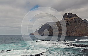 large pebble mountain by the calm sea in an arid environment of the canary islands under cloudy skies