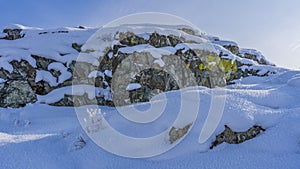 A large picturesque boulder is covered with a layer of snow.