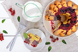 A large piece of cottage cheese cake with summer berries, jam and a jug of milk