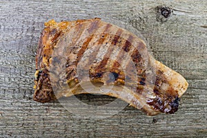 Large piece of fresh pork meat on a bone prepared on a grill pan on old wooden table for background