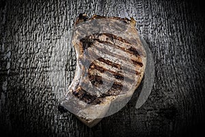 Large piece of fresh pork meat on a bone prepared on a grill pan on old wooden table for background. Toned