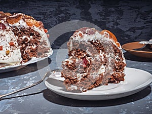 A large piece of homemade cake on a saucer shot close-up, in the background a cake