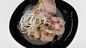 A large piece of pork on a black plate. Rotating in a circle close-up.