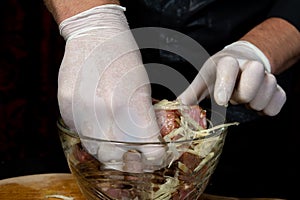 A large piece of pork is cut into pieces, marinated by the chef with spices, and the chef rubs the potatoes on a grater to the