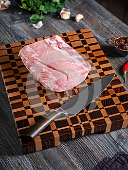 Large piece of pork meat and kitchen knife on a beautiful wooden board