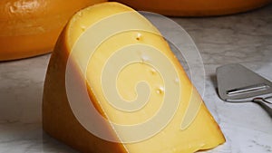 Large piece of traditional mature Dutch Gouda cheese on a marble table