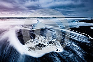 Large pieces of the iceberg that sparkle on the black sand. Location place Jokulsarlon, Vatnajokull national park, Iceland