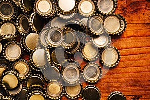 Large pile of beer bottle caps on wooden desk