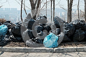 A large pile of black garbage bags. Garbage removal on the city streets. Seasonal cleaning of city streets