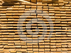 A large pile of boards sawn from trees on a sawmill for the procurement of building materials for construction. Construction