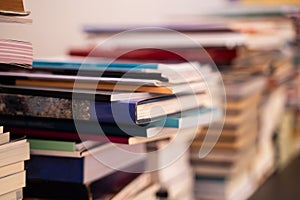A large pile of books is stacked on a blurred background