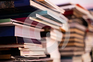 A large pile of books is stacked on a blurred background