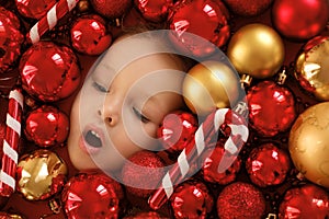 A large pile of Christmas red and gold sparkling balls surrounds the child`s face.