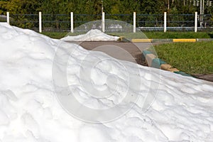 Large pile of dirty snow (ice) lies in the summer on the road an