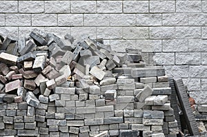 A large pile of disassembled paving tiles against the wall of light bricks
