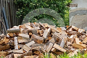 A large pile of freshly chopped firewood stacked in an outdoor rustic setting, ready for winter warmth.