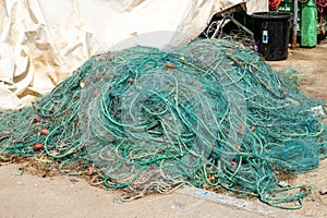 Pile of green fishing nets with cork floats, ropes, and white tarp photo