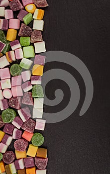 A large pile of mixed sweets on wooden background