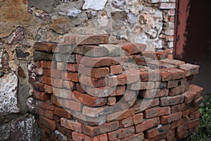 a large pile of red-orange bricks against the background of a broken old wall on the street. for introductory instructions books photo