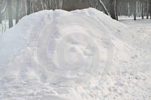 A large pile of snow piled in the Park for the construction of an ice slide, copy space, natural background