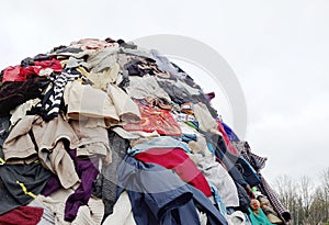 Large pile stack of textile fabric clothes and shoes. concept of  fashion industry pollution, sustainability, reuse of garment.