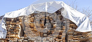 Large pile stack of timber protected by waterproof canvas tarps photo