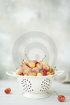 large pink cherries in a white colander